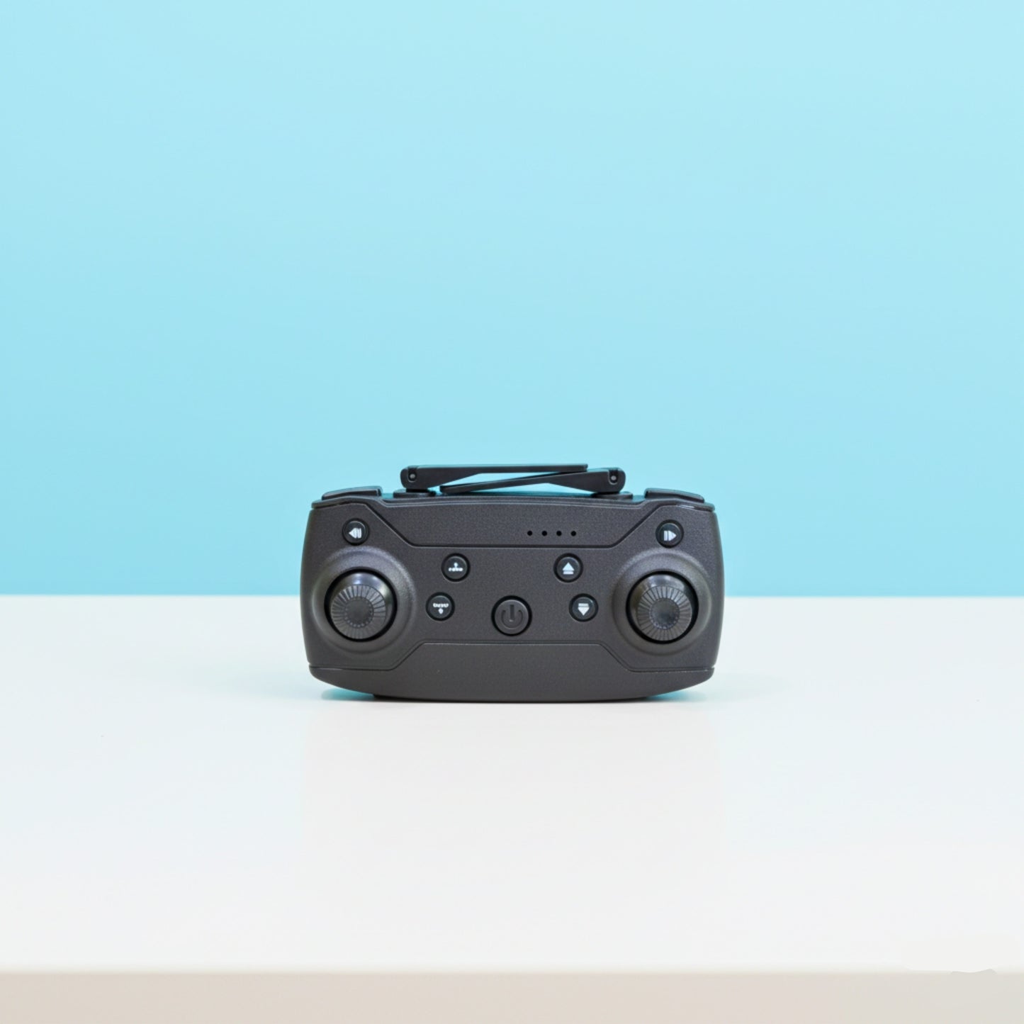 Black remote control device on a white surface with a light blue background